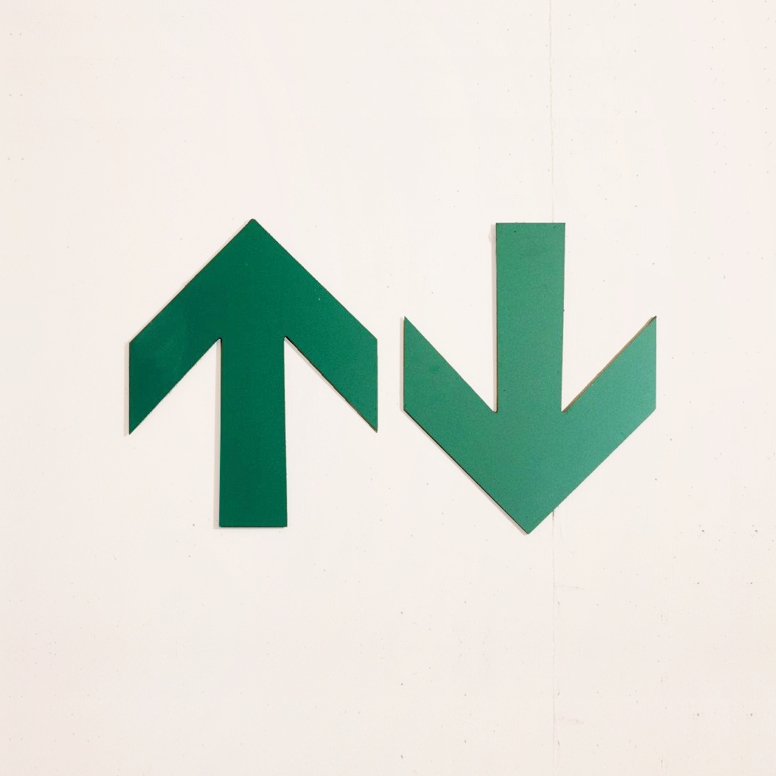 Zwei grüne Pfeile auf einer Betonwand zeigen nach oben bzw. nach unten